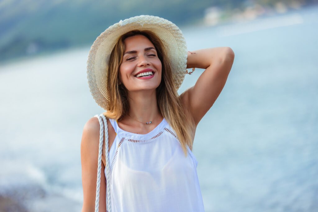 Woman wearing a sun hat outside enjoying the beach in the summer
